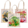 Three tote bags with personalized names and tropical designs on a white background